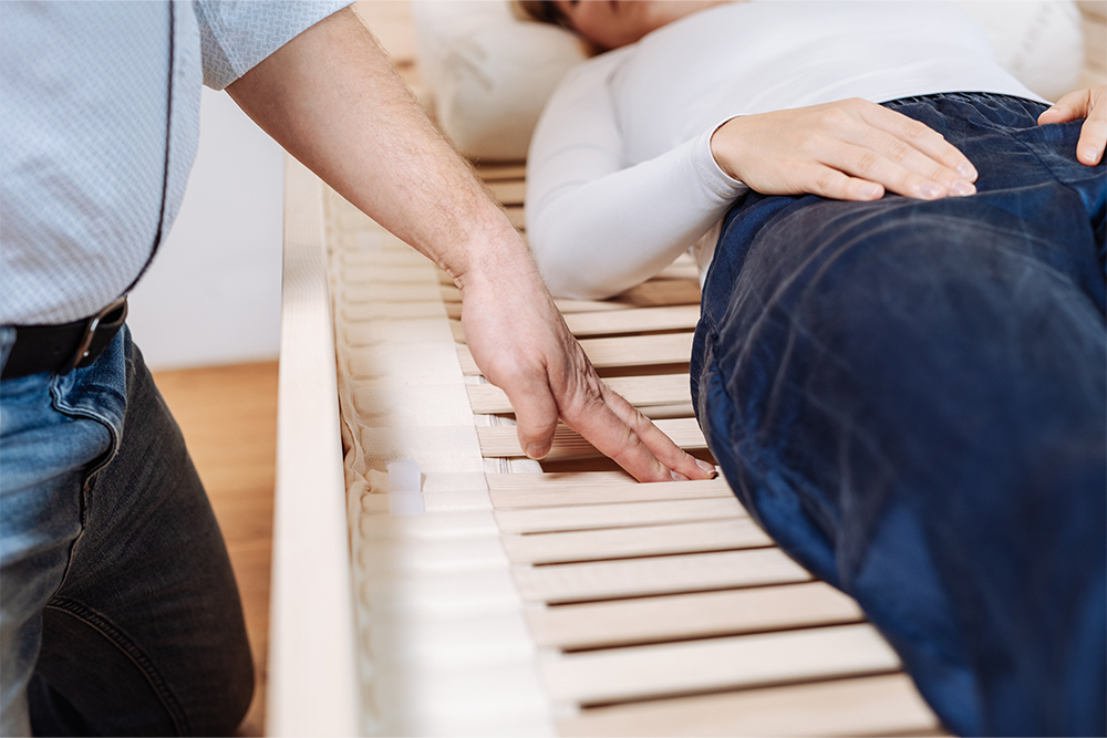 Berater prüft die flexible Unterfederung unter einer seitlich liegenden Person