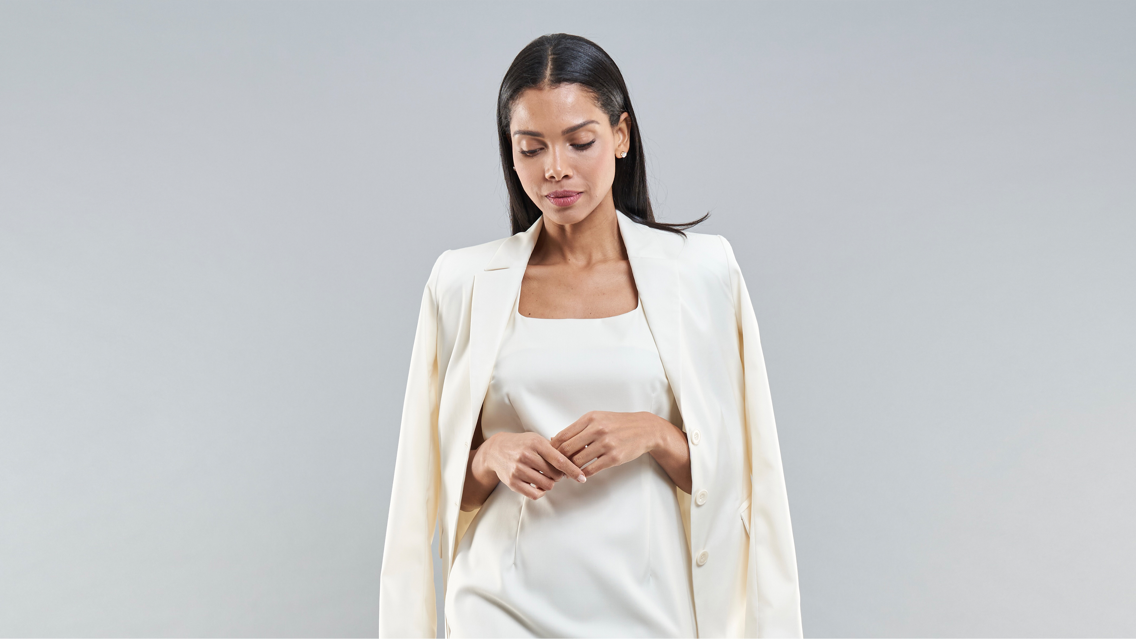 Dame mit einem weißen Satinkleid und einem weißen Blazer drüber